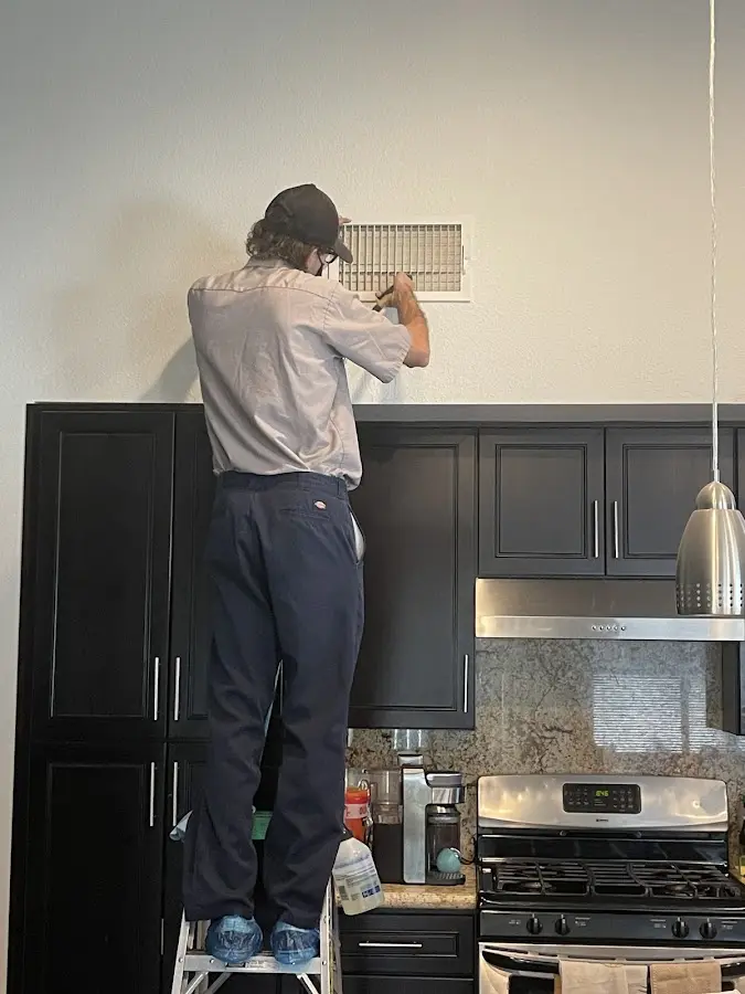 Technician inspecting an air vent during HVAC service in Brentwood